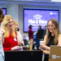 Three young women looking at student presentation
